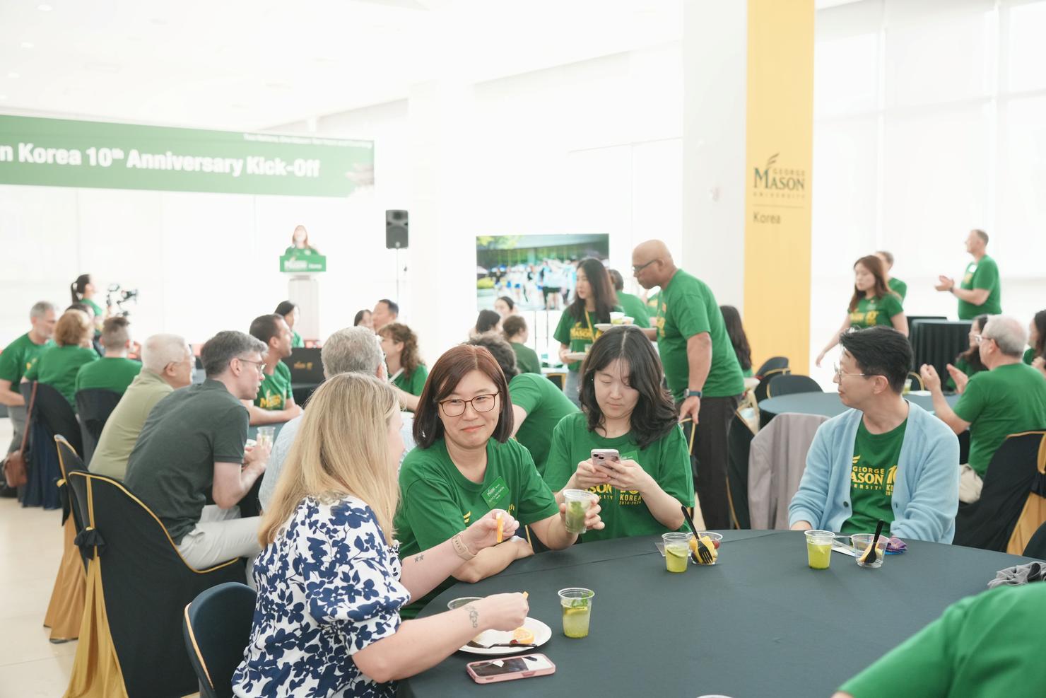 Attendees sit at tables and chat during the Mason Korea anniversary kickoff celebration
